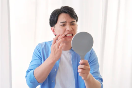 鏡で歯並びや顔の左右差を気にする男性